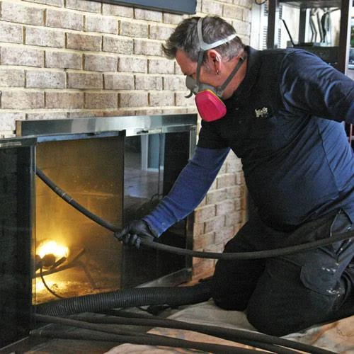Technician wearing respiratory protection while working at a brick fireplace