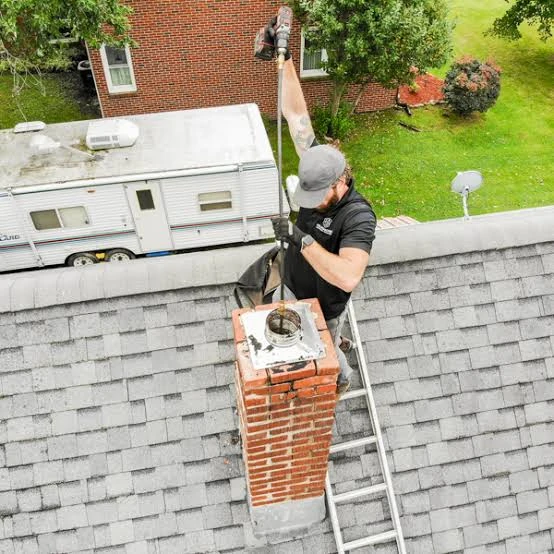 Overhead view of a technician working a cleaning rod through a chimney flue